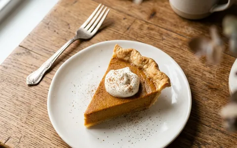 A white plate of a sliced pumpkin pie, photographed from above.